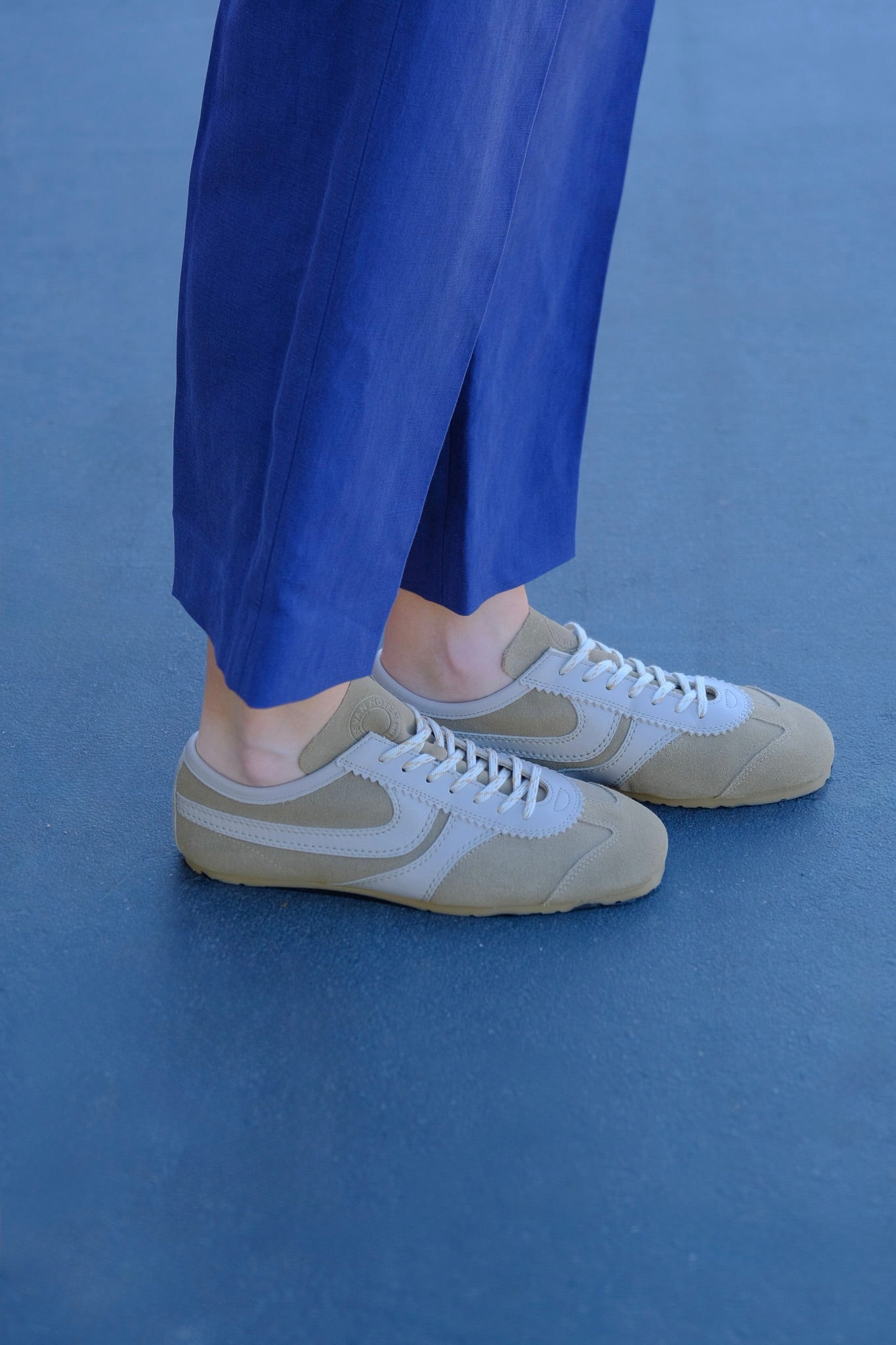 Beige suede low-top sneakers from Dries Van Noten with stitched panel details and a contrasting rubber sole. Available in Brentwood, CA and Charlotte, NC.