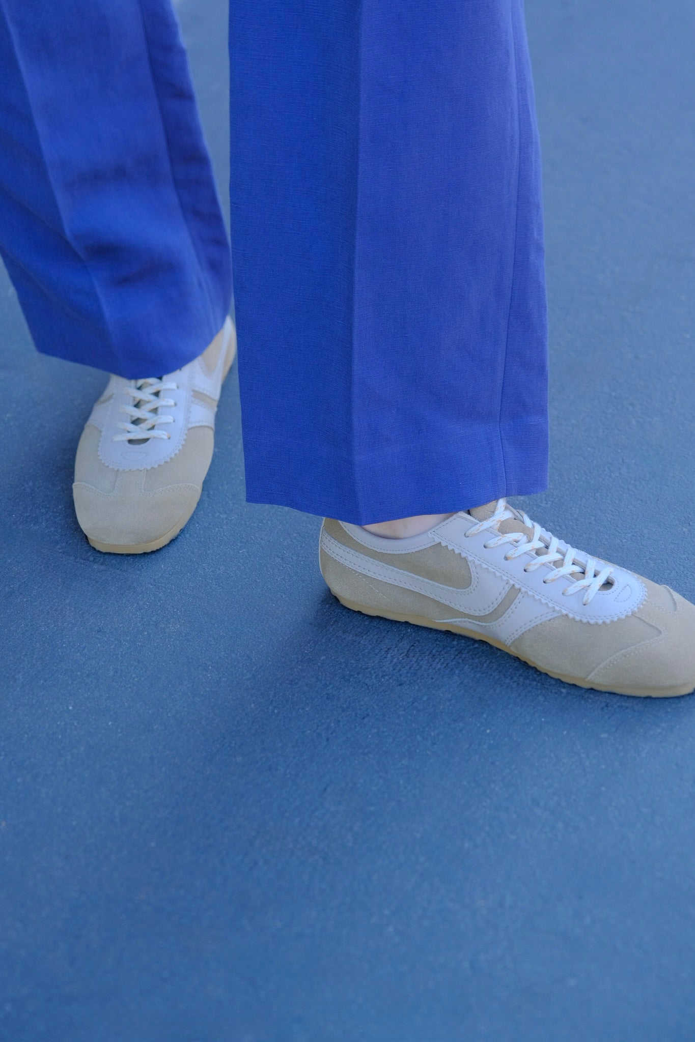 Beige suede low-top sneakers from Dries Van Noten with stitched panel details and a contrasting rubber sole. Available in Brentwood, CA and Charlotte, NC.