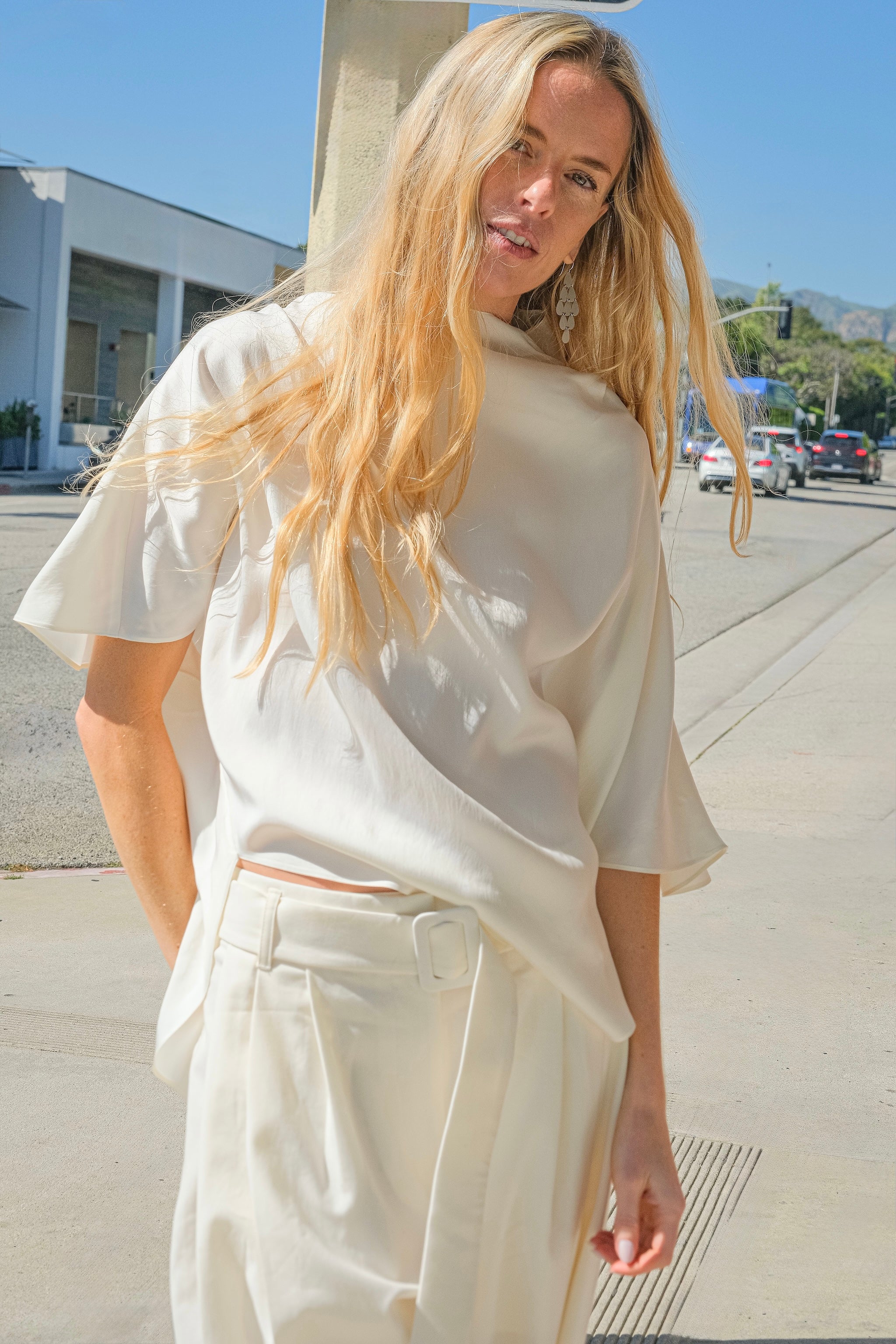 Ivory draped silk-viscose blend blouse from Petar Petrov with a relaxed silhouette and asymmetric hem. Available in Brentwood, CA and Charlotte, NC.