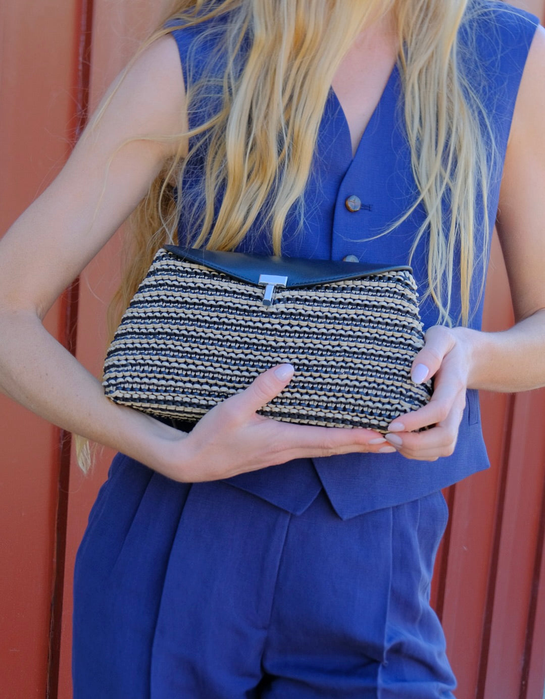 Black and sand woven leather clutch from Totême with a T-lock closure and refined minimal silhouette. Available in Brentwood, CA and Charlotte, NC.
