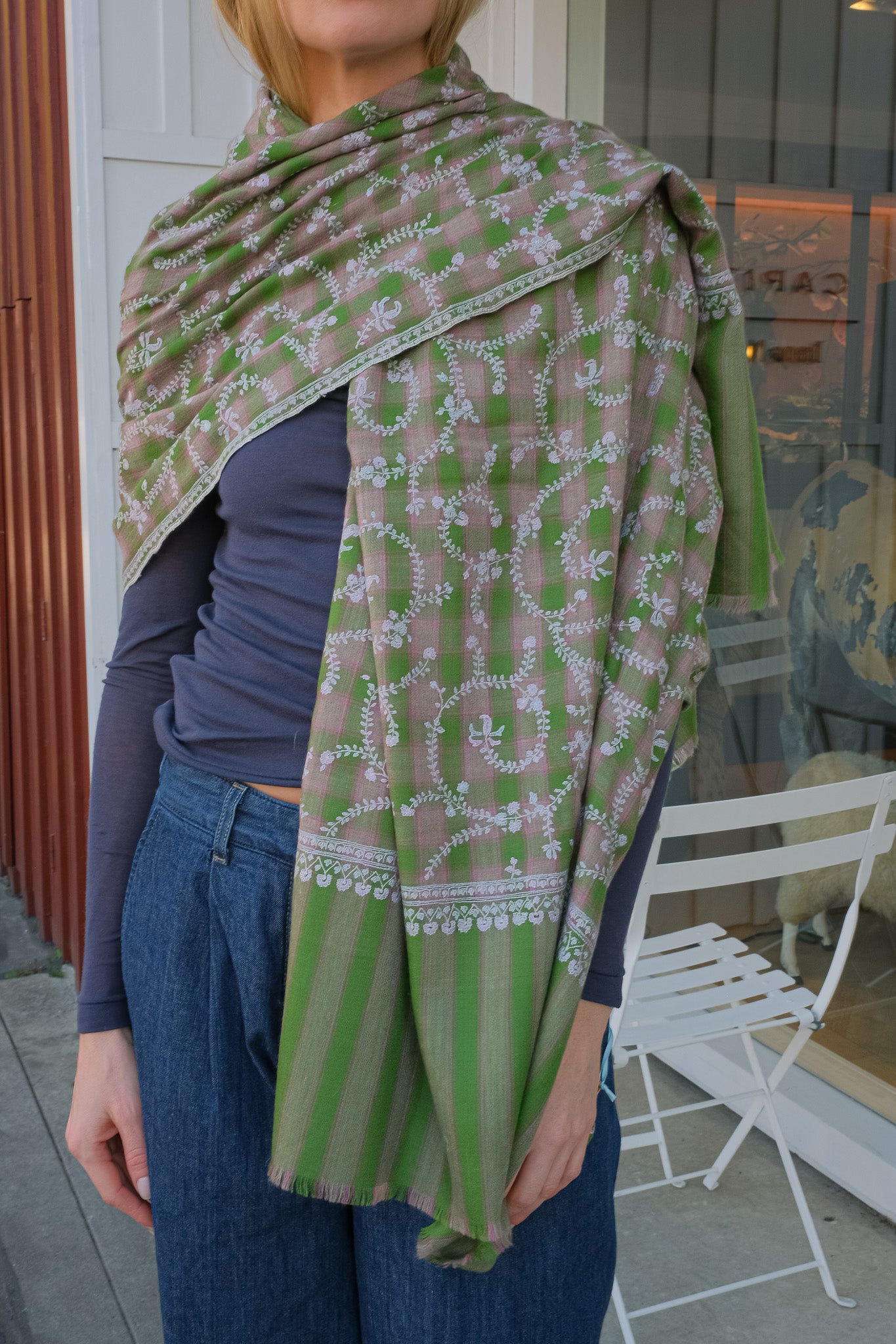 Person wearing a green and white patterned shawl outdoors.