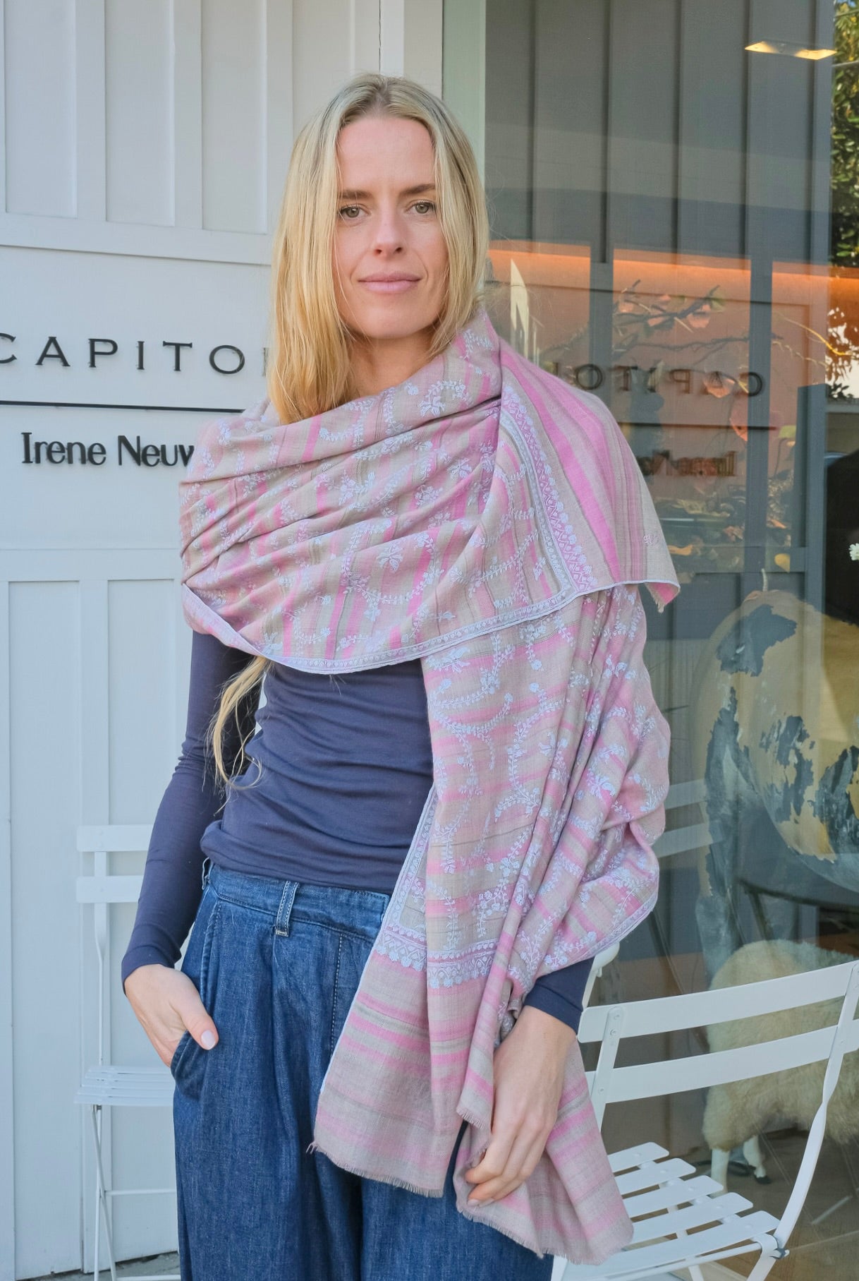 Woman wearing a pink patterned shawl in front of a store.