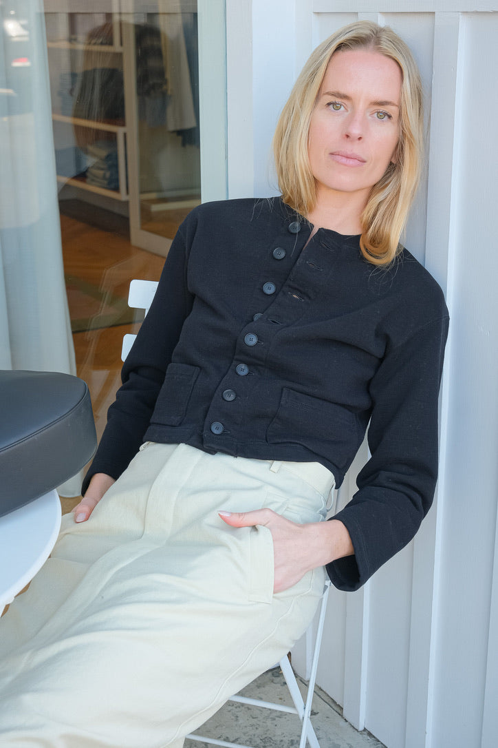 Black cardigan jacket from Auralee. Button front and long sleeves with two front pockets. Available in Charlotte, NC and Brentwood, CA.