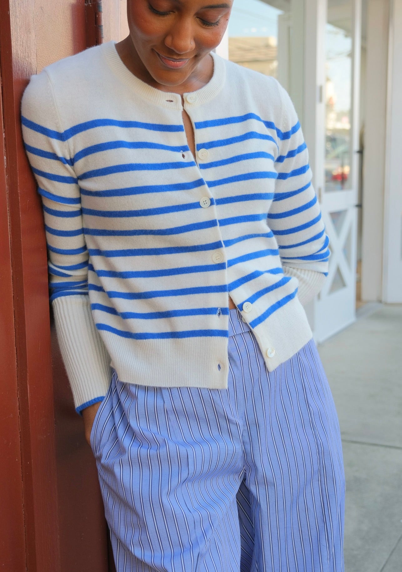 Person wearing a blue and white striped cardigan and pants on a porch.