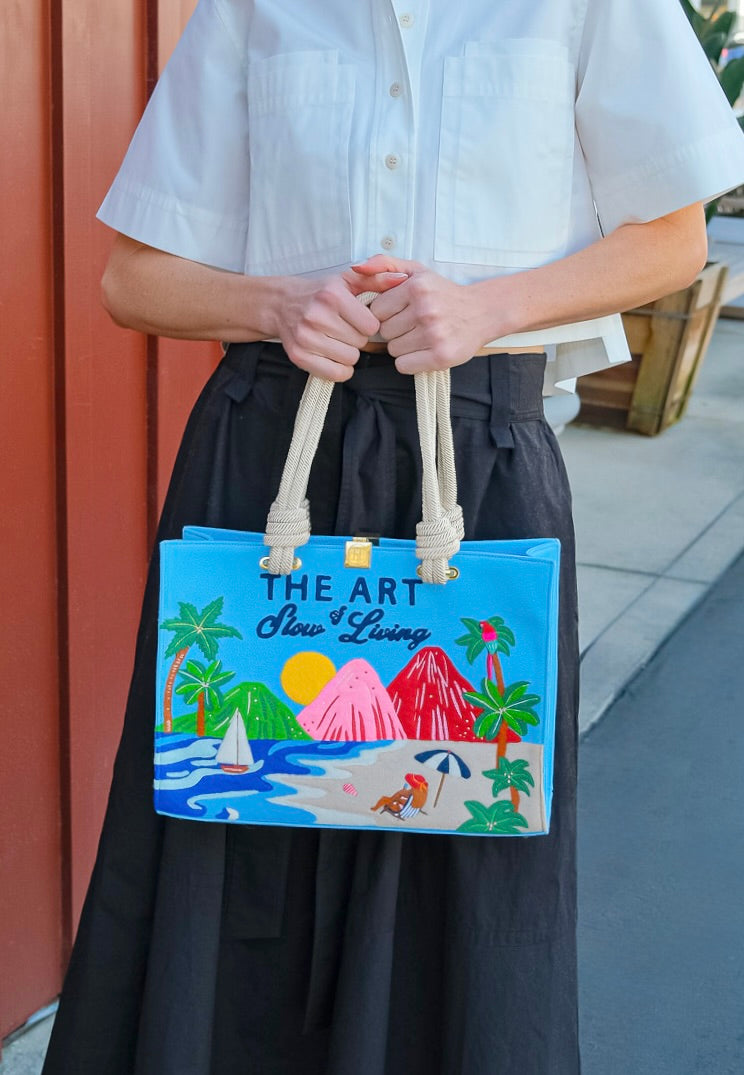 Olympia Le Tan medium sized tote with a teal background, beach design, and "The Art of Slow Living" embroidery. Available in Brentwood, CA.