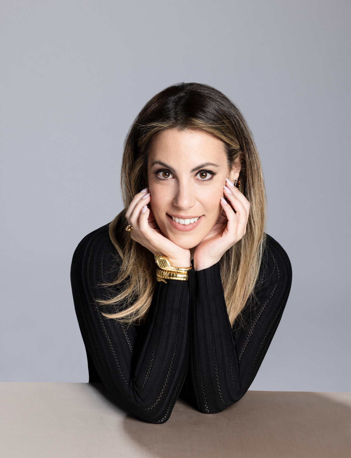 Woman with hands under chin on a gray background