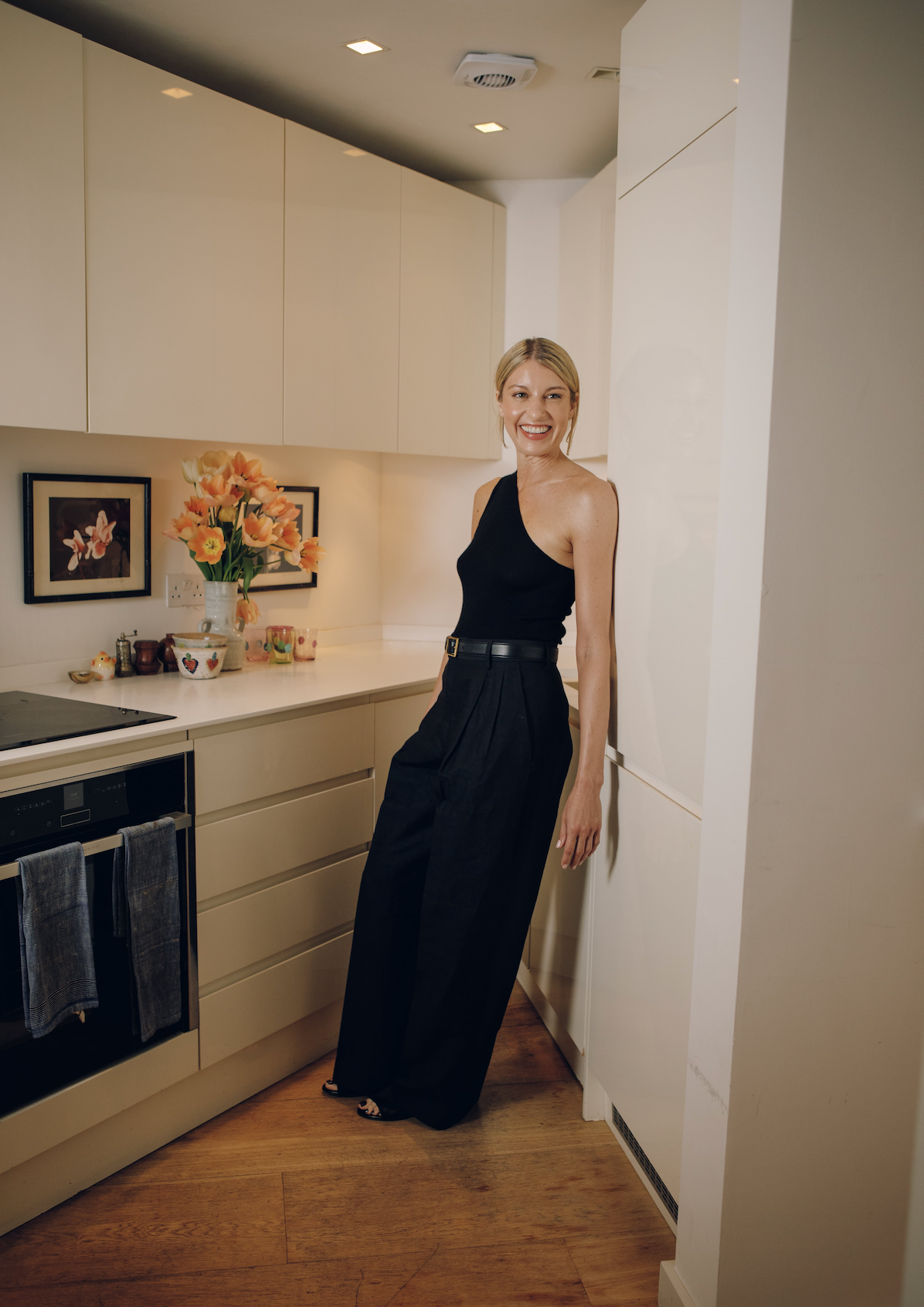 Woman in a black dress standing in a modern kitchen.