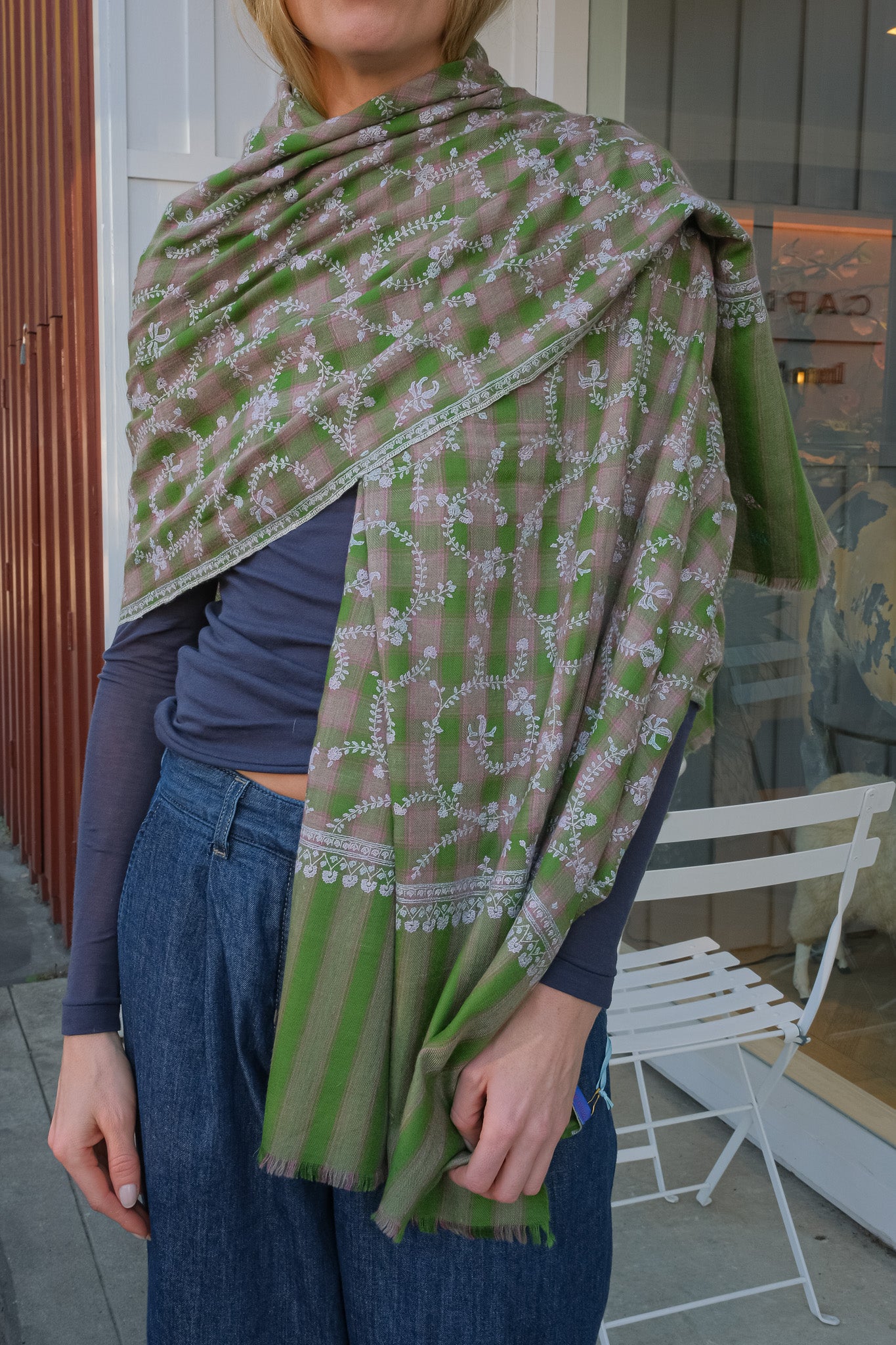 Person wearing a green and brown patterned shawl outdoors.