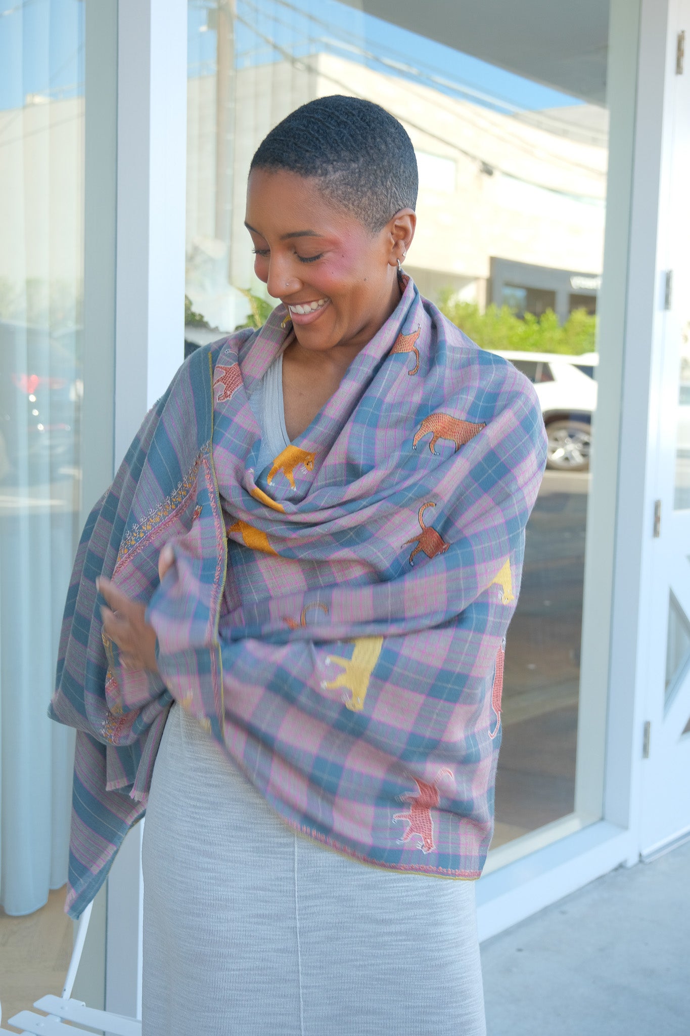 Yaser Shaw animal embroidered shaw on pink and grey plaid background. Available in Brentwood, CA and Charlotte, NC.